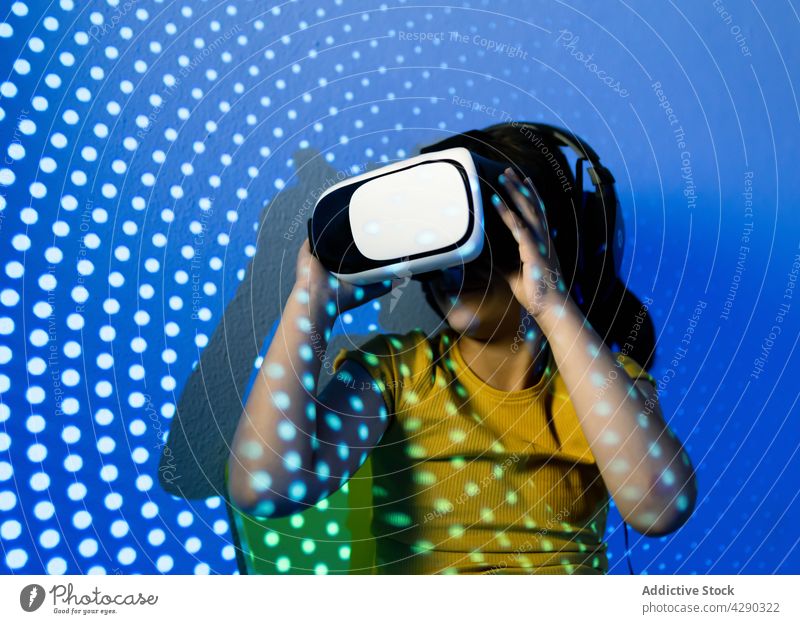 Joyful girl in VR goggles in neon lights vr experience excited joyful cheerful entertain headset expressive device fun laugh virtual reality carefree studio