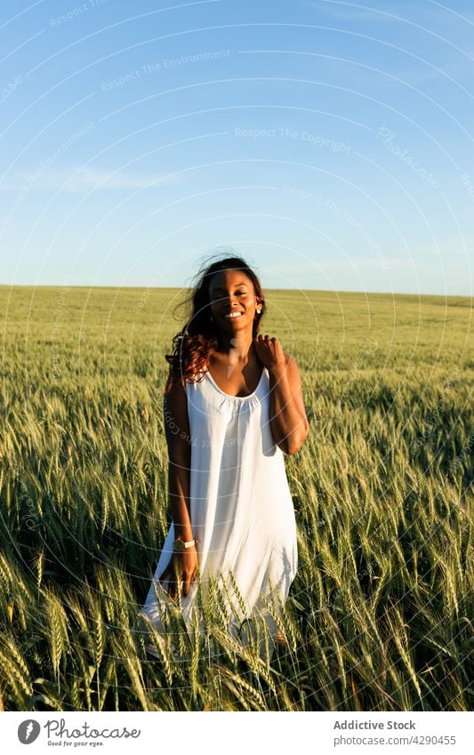African American female in dress walking on grassy meadow woman wheat field smile countryside harmony calm alone blue sky flora black african american young