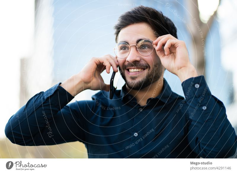 Young man talking on the phone outdoors. young mobile urban smiling smile connection gadget portrait positive wireless telephone holding walking looking typing