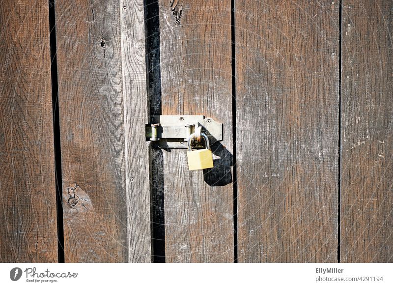 Old wooden wall of a barn with a simple lock. Wooden wall Brown completed Lock Padlock door Barn Wooden door Closed Simple background Metal Metal lock Entrance