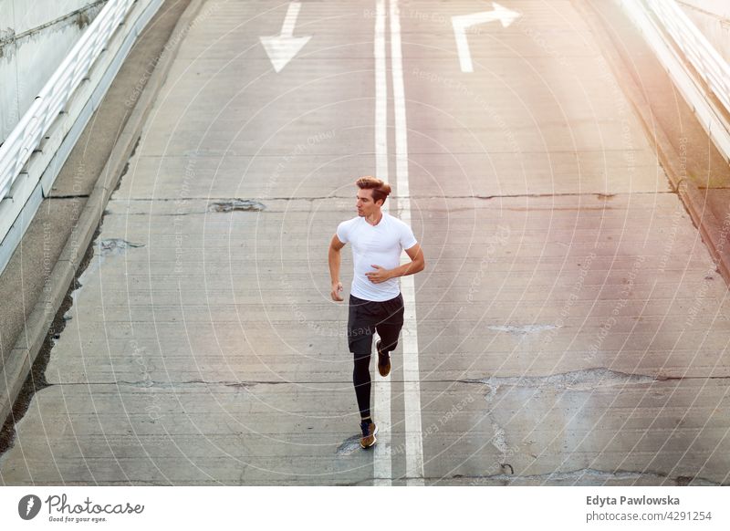 Young man running on parking level in the city at sunset Jogger runner jogging people young male energy exercise clothing exercising fitness recreation sport