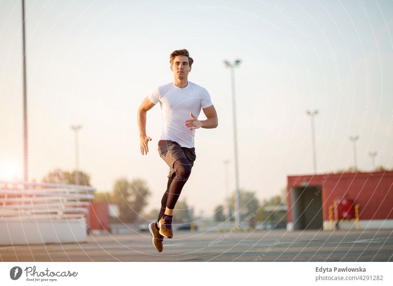 Young man running on parking level in the city at sunset Jogger runner jogging people young male energy exercise clothing exercising fitness recreation sport