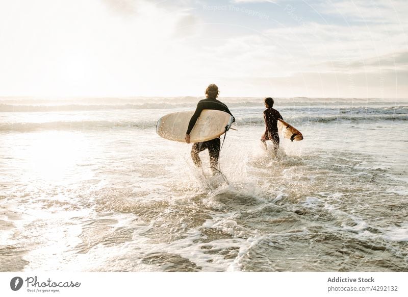 Anonymous surfer friends at the beach with surfboards nature sunset wave outdoors wetsuit seacoast together sportsman surfing hobby male ocean men people