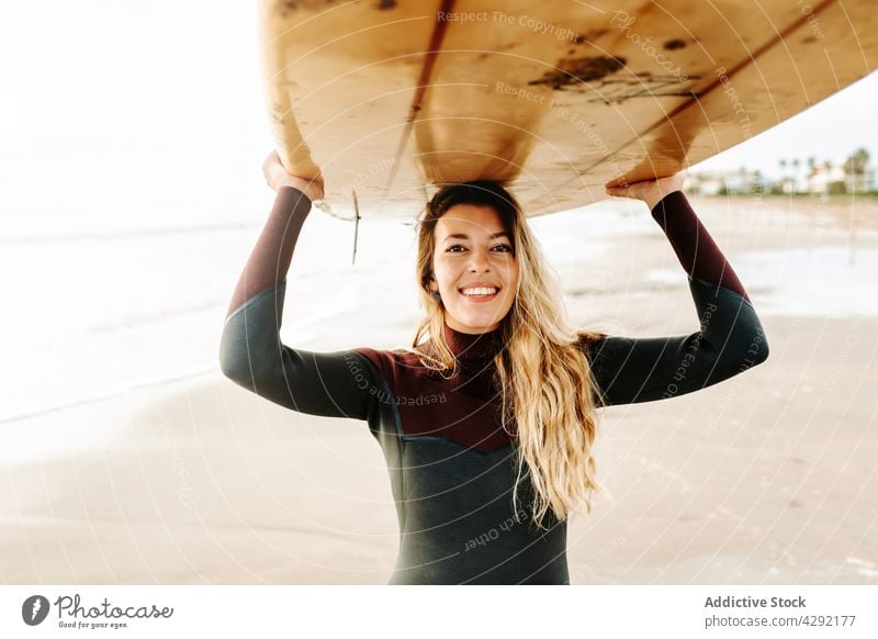 Happy female surfer standing at the beach with surfboard woman nature sunset wave outdoors wetsuit seacoast smile glad sportswoman delight happy surfing