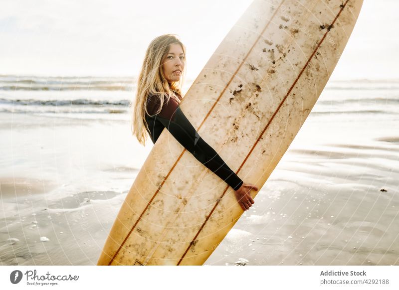 Female surfer standing at the beach with surfboard woman nature sunset wave outdoors wetsuit seacoast female sportswoman surfing hobby ocean seaside calm water