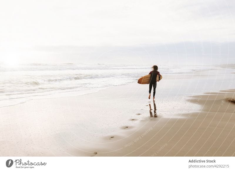 Anonymous surfer at the beach with surfboard man nature run sunset wave outdoors wetsuit seacoast male sportsman surfing hobby ocean seaside calm catch water