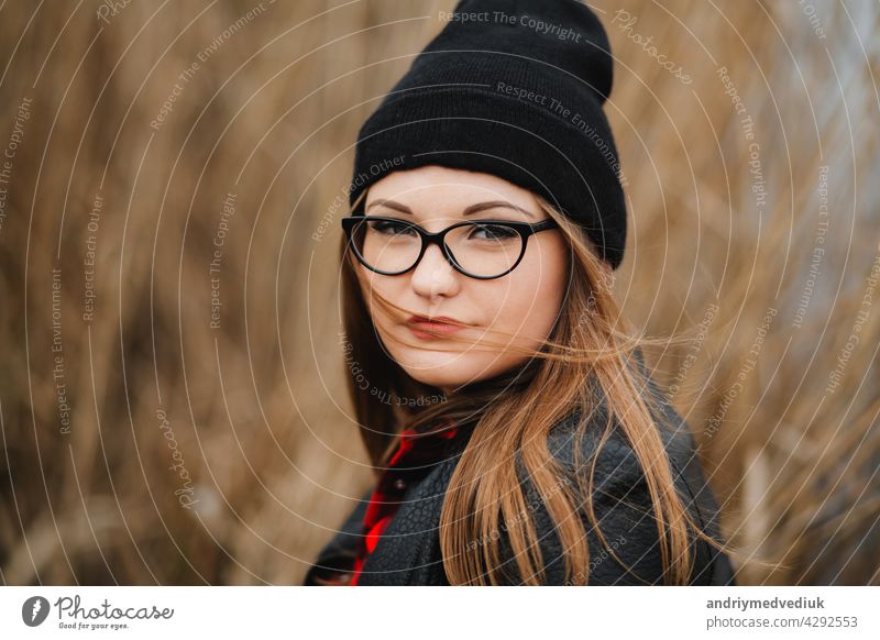 portrait of a beautiful young girl near the lake in the reeds in a dark leather jacket and glasses autumn park woman smile map outdoor nature lifestyle