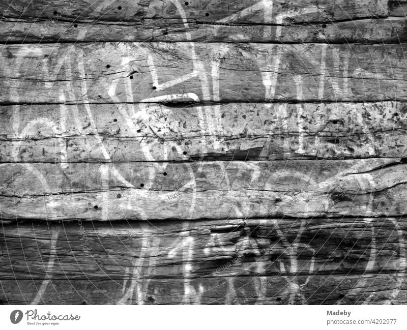 White outlines of large letters as graffiti on an old house wall at the old harbour in Offenbach am Main in Hesse, photographed in classic black and white
