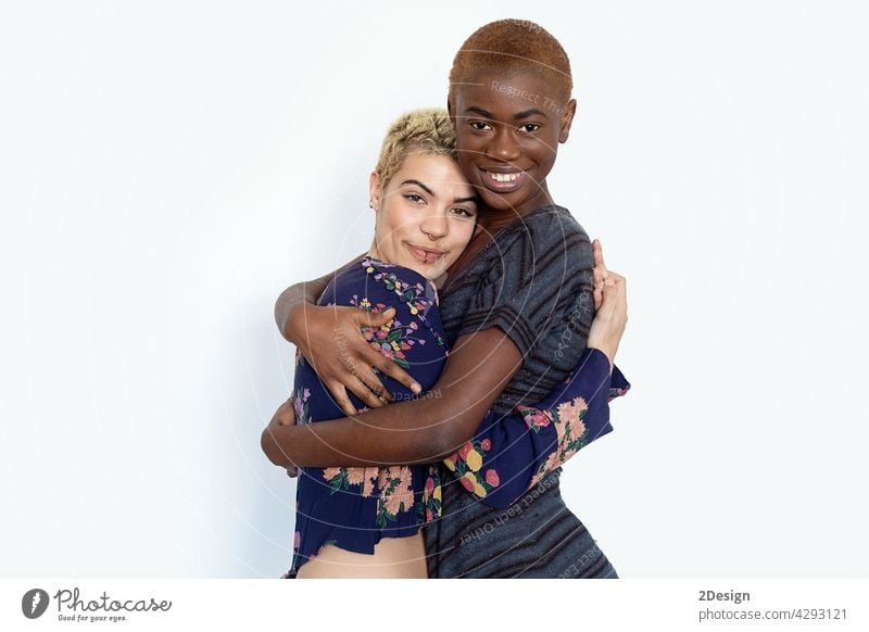 Photo of joyful ladies embrace and enjoy togetherness, being of different of races, dressed in casual jumpers, isolated over white background bestfriend