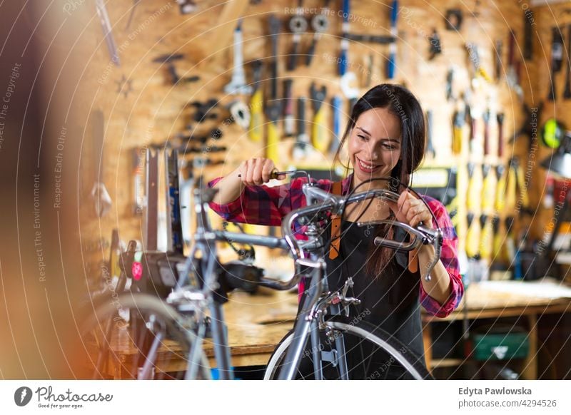 Young woman working in a bicycle repair shop sales clerk bicycle mechanic bicycling bike shop business retail helpful indoors female manager owner profession