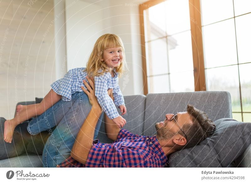 Happy father playing with daughter on sofa at home house man dad family parent relatives child girl little girl kid kids children relationship together