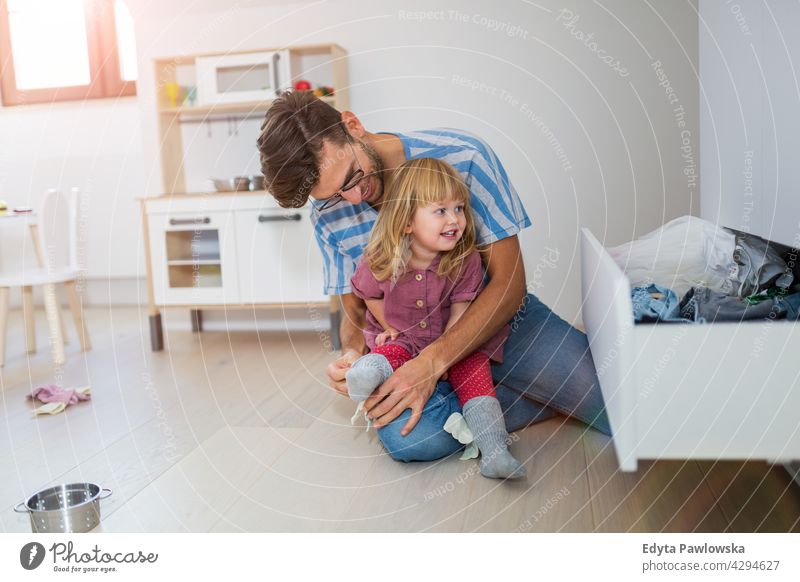 Dad is helping toddler daughter to get dressed home house man dad father family parent relatives child girl little girl kid kids children relationship together