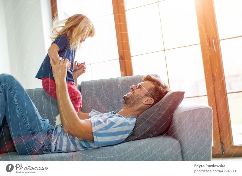 Happy father playing with daughter on sofa at home house man dad family parent relatives child girl little girl kid kids children relationship together