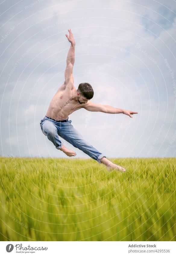 Graceful male ballet dancer jumping in countryside field man nature grass grace freedom sensual shirtless energy inspiration agile summer active carefree art
