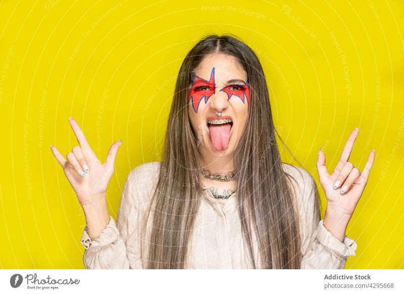 Woman gesturing rock sign and showing tongue woman rock and roll show tongue gesture creative makeup horn style colorful bright female young music fashion model