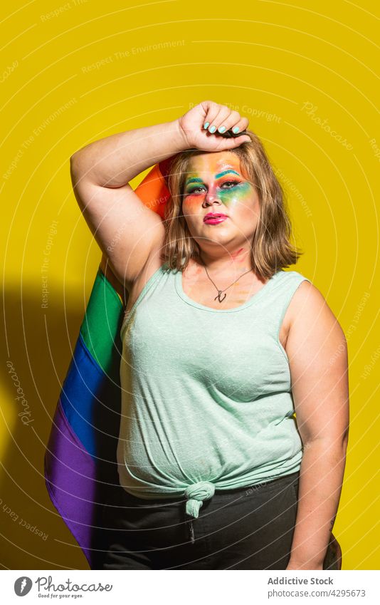 Plus size woman with LGBT flag touching head lgbt pride makeup creative touch head support colorful bright female rainbow body positive multicolored symbol