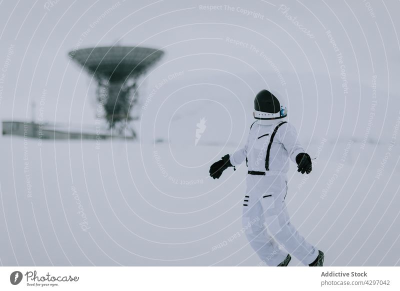 Spaceman in snowy field with dish satellites spaceman cosmonaut astronaut radar winter white antenna svalbard norway spacesuit costume cold explorer valley