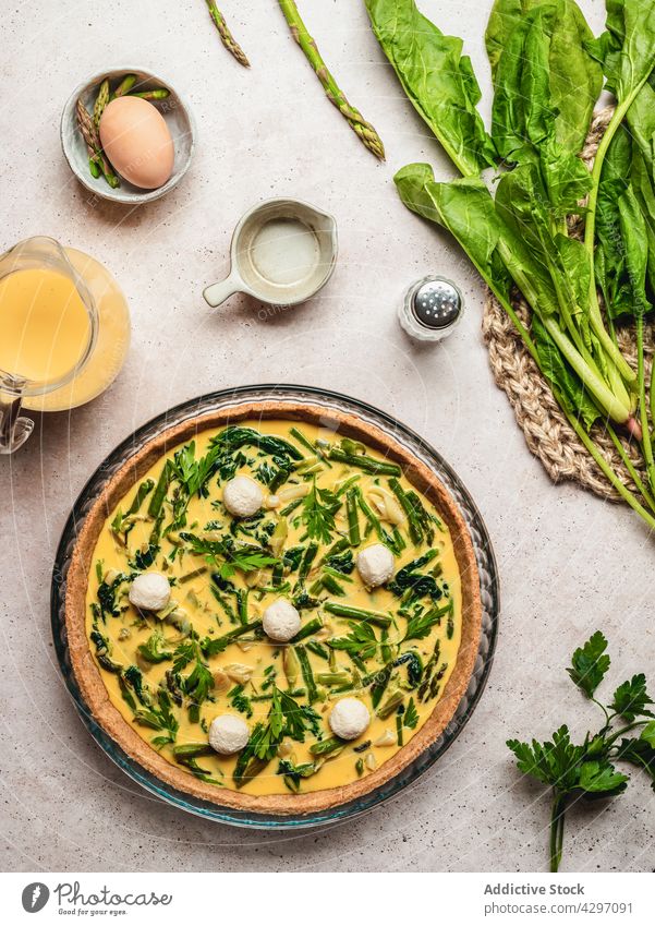 Delicious quiche placed near ingredients tart dish food spinach asparagus egg parsley fresh nutrition cuisine vegetable french tradition authentic organic herb