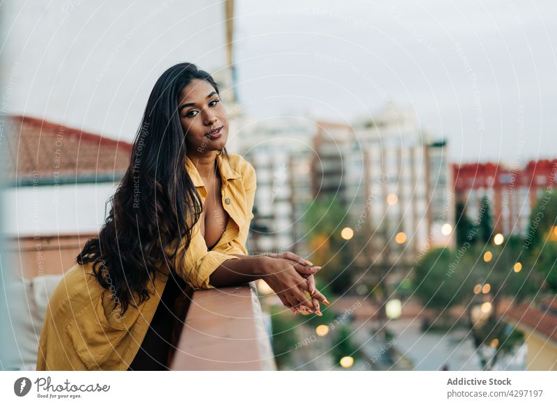 Hispanic woman chilling on balcony in evening rest lean railing city weekend home street casual female ethnic young hispanic terrace trendy lifestyle relax