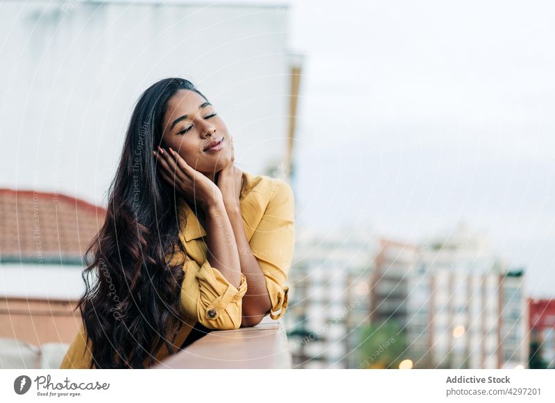 Happy Hispanic woman chilling on balcony in evening rest smile lean railing city weekend eyes closed home happy street casual female ethnic young hispanic