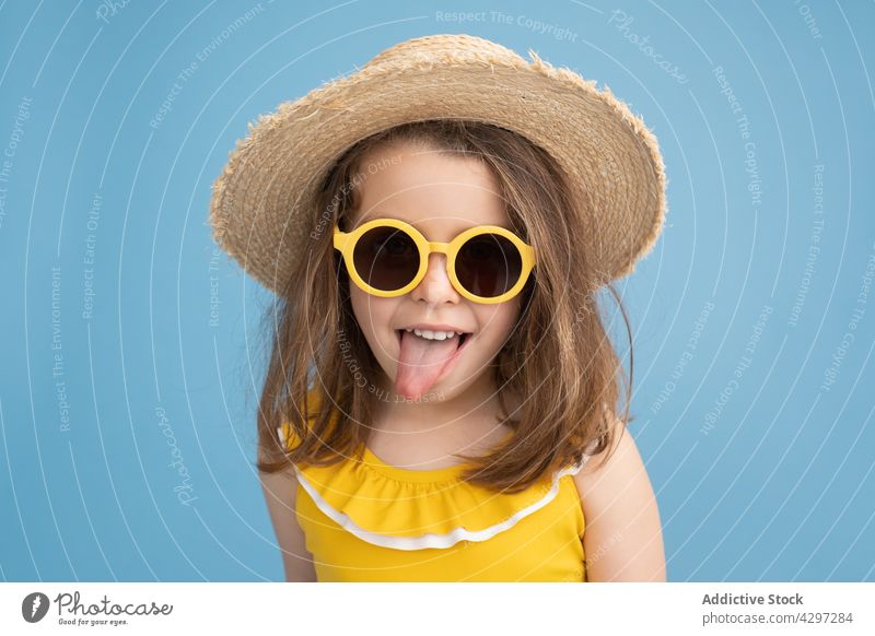 Little girl in yellow sunglasses showing tongue summer style fashion show tongue playful happy kid smile beach child cute little having fun bright cheerful