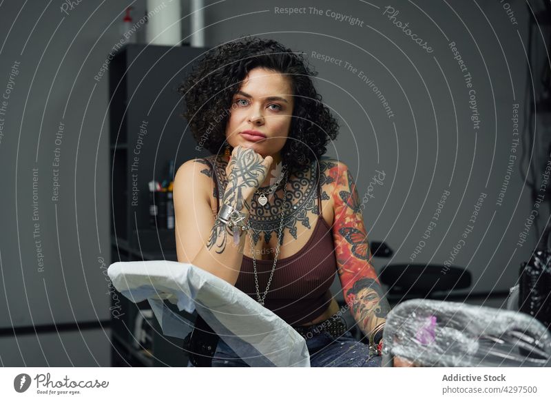Confident female with tattoos in tattoo studio woman confident alone informal salon serious accessory adult appearance individuality rebel brutal light creative