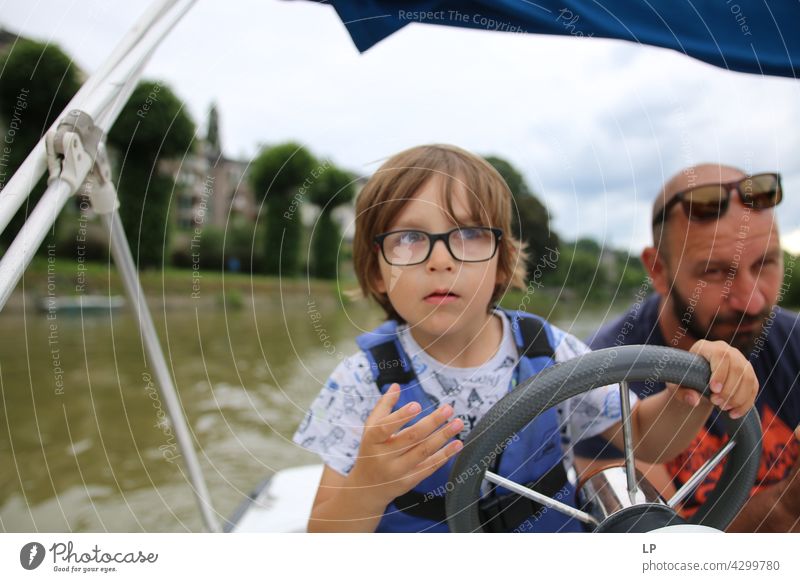 child wearing glasses looking to the horizon and stiring a boat Human being Emotions Child Parents Family & Relations happiness childhood playing Playful