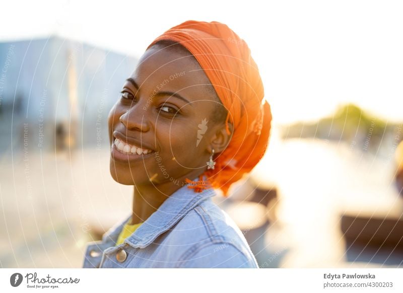 Young woman in orange head wrap at sunset afro proud real people city life African american afro american student Black ethnicity sunny outside pretty girl