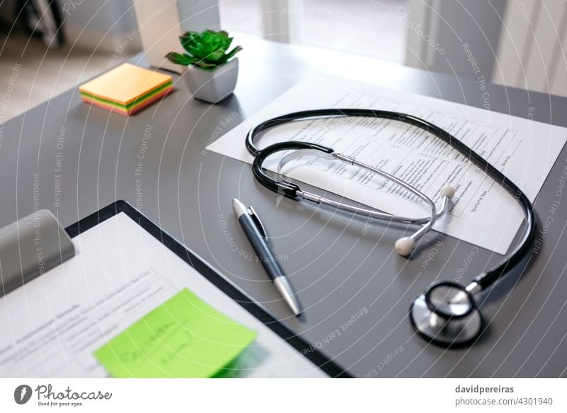 Doctor desk with stethoscope and documents medical documents doctors desk clipboard pen nobody plants table equipment interior health care consultation clinic