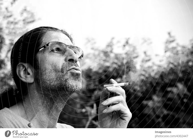 Smoking. Side view of man with long hair and beard smoking. Smoke exhaling. Smoker holding smoking cigarette in hand side view Man Facial hair exhale Hand