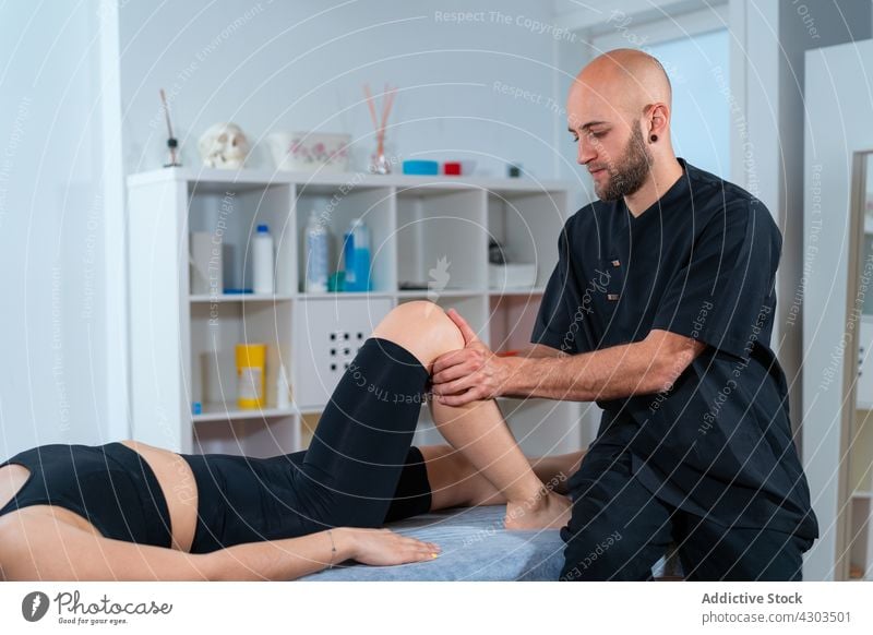 Physical therapist examining leg of crop sportswoman in hospital check up patient recovery rehabilitation health care physiotherapy athlete table clinic