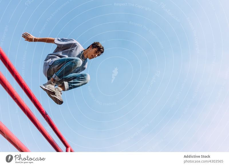 Young man jumping over railing in city parkour trick stunt obstacle moment fence urban male acrobatic fearless extreme activity metal freedom perform
