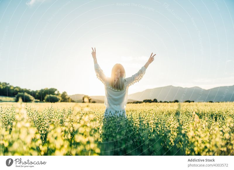 Happy woman showing V sing in countryside field freedom two fingers peace nature v sign happy white dress hippie style flower tranquil calm harmony slim meadow