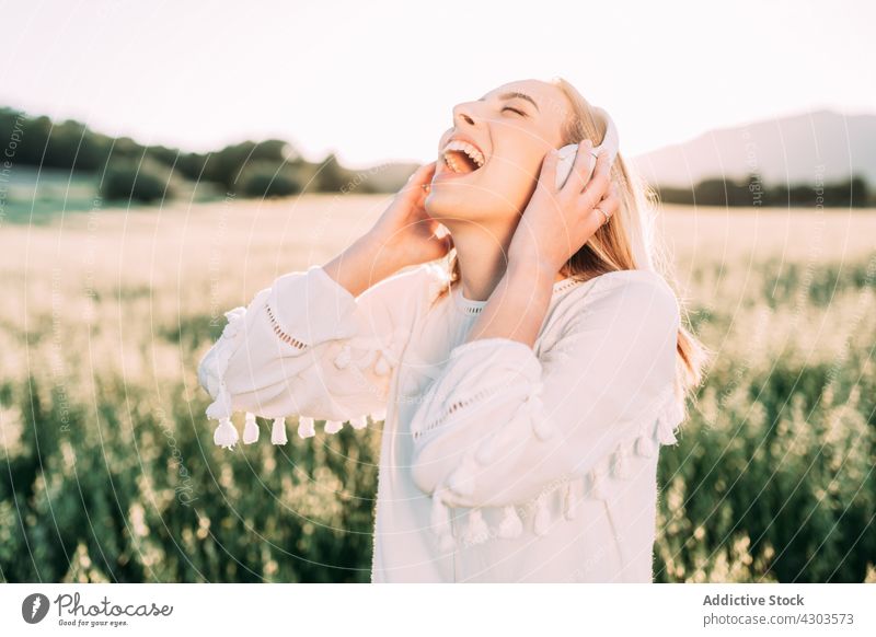 Happy woman listening to music with headphones in summer nature excited freedom field countryside eyes closed cheerful carefree relax fun content positive rest