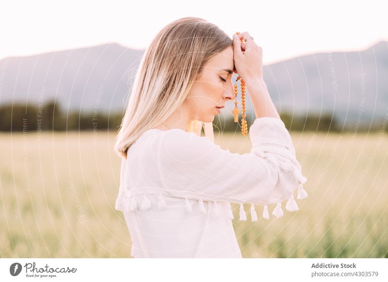 Calm female praying with cross in field woman nature calm faith belief harmony peace tranquil religion wish serene meadow rural pure white dress eyes closed