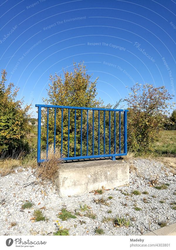 Blue steel railing with concrete foundation alone in front of a blue sky in sunshine in Oelde near Warendorf in Westphalia in the Münsterland region of Germany