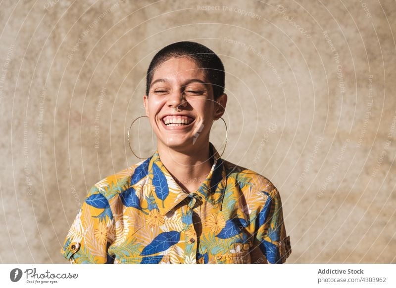 Cheerful ethnic woman in shirt with floral ornament in sunlight cheerful laugh candid style friendly portrait individuality bisexual sincere identity gender