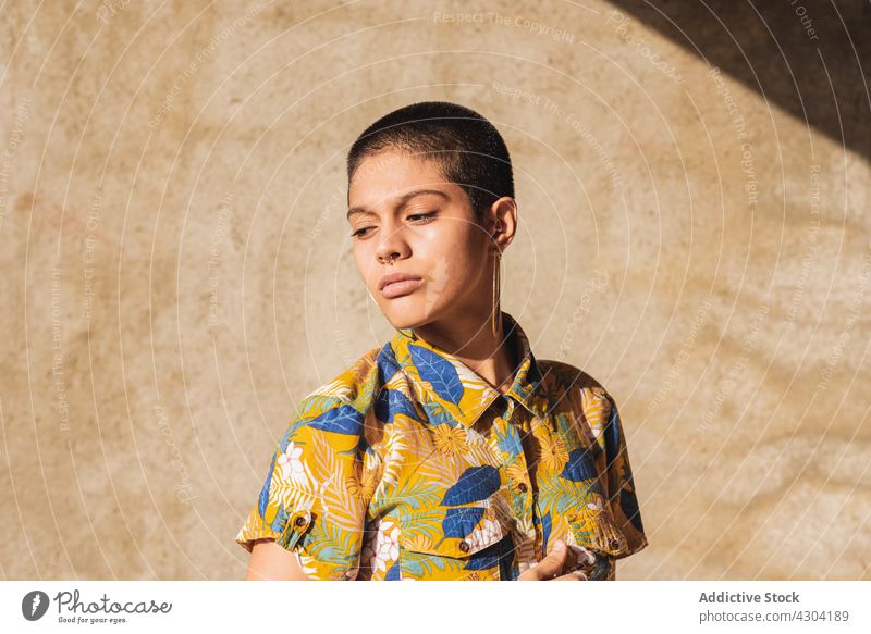 Ethnic woman in shirt with floral ornament in sunlight bisexual gender identity cool individuality vain portrait shadow contemplate contemporary generation