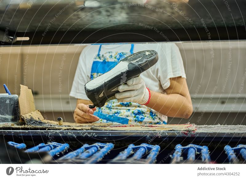 Detail of worker applying glue to the shoes sole in a production line manufacture factory shoes factory quality working at work employee task people China