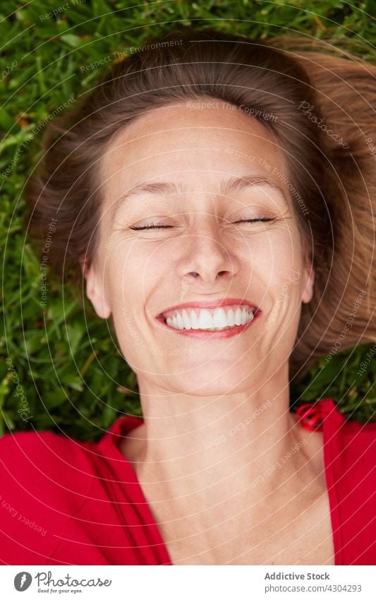 Woman dressed in red lying on the ground in a park with grass nature woman summer green young beautiful people female girl happiness happy meadow caucasian