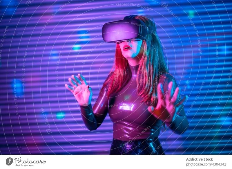 Young female exploring virtual reality woman vr explore interact headset gesture immerse neon illuminate futuristic young goggles innovation technology