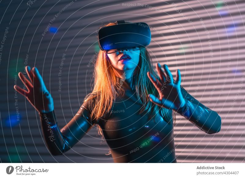 Young female exploring virtual reality woman vr explore interact headset gesture immerse neon illuminate futuristic young goggles innovation technology