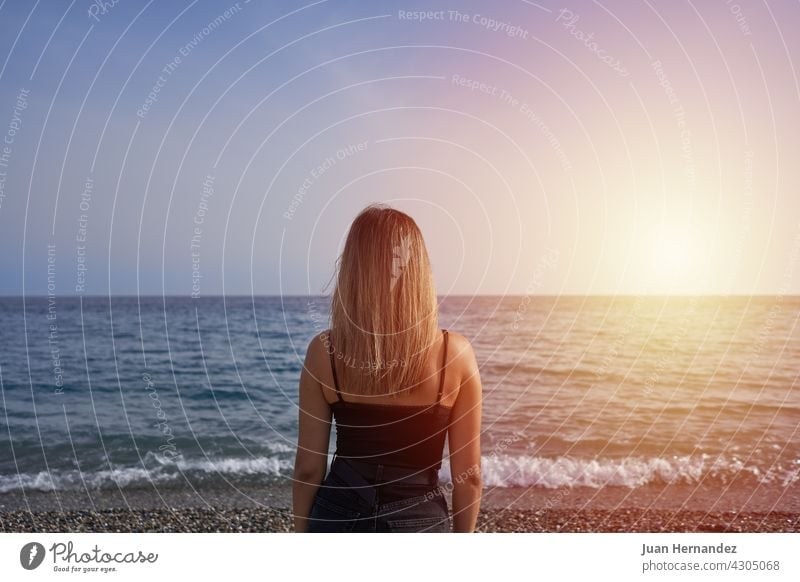 woman looking at the horizon in the sea. young beach sunset relaxation freedom carefree horizontal enjoy enjoyment standing young adult back one person alone