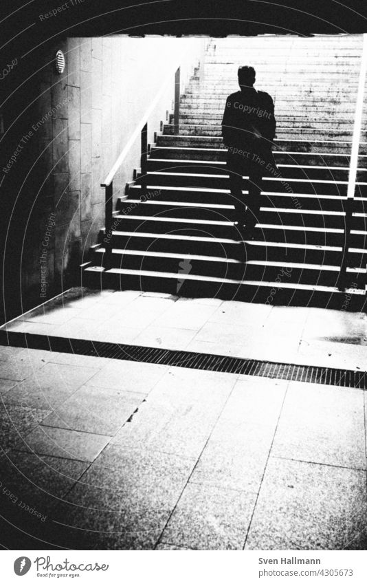 man climbs a staircase Stairs Staircase (Hallway) black-and-white Descent step Dark stair treads stagger Legs Old town Metal metal grid Metal railings Diagonal