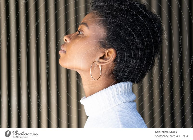 Young African American female near striped building wall woman smile happy style urban street city outfit fashion african american black ethnic young earring