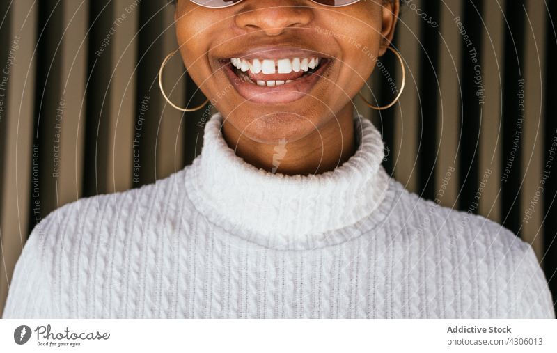 Crop black woman cheerfully smiling smile style street urban modern wall happy fashion sweater female earring accessory joy gapped teeth african american ethnic