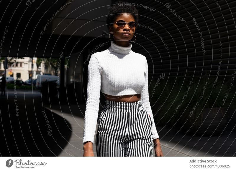 Trendy African American woman with sunglasses style street city modern sunny daytime urban female stroll trendy town appearance outfit fashion young ethnic