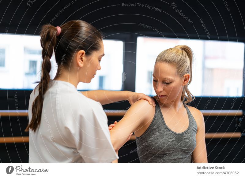 Physiotherapist fitting shoulder joint of woman osteopath pain patient physiotherapy clinic session rehabilitation injury women ache recovery client doctor