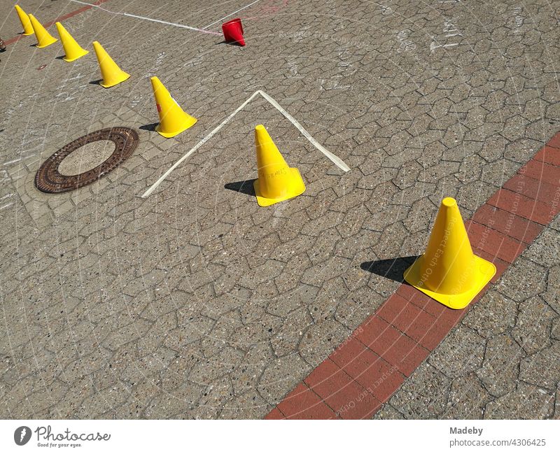 Bright yellow Lübeck hats in the sunshine on the interlocking pavement of a schoolyard at a school festival in Oerlinghausen near Bielefeld in the Teutoburg Forest in East Westphalia-Lippe