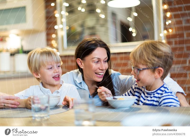 Mother and children at breakfast family parent parents relatives relationship woman female mom mother people two three adult son boy kid kids happy lifestyle